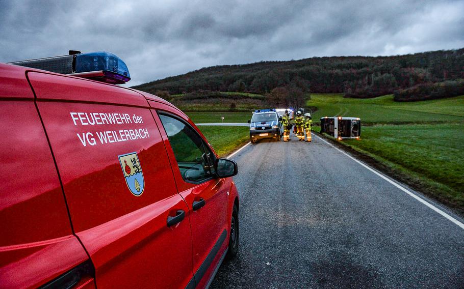 A police vehicle is parked a short distance from an overturned bus near Weilerbach, Germany, on March 10, 2023. The cause of the crash is still undetermined.