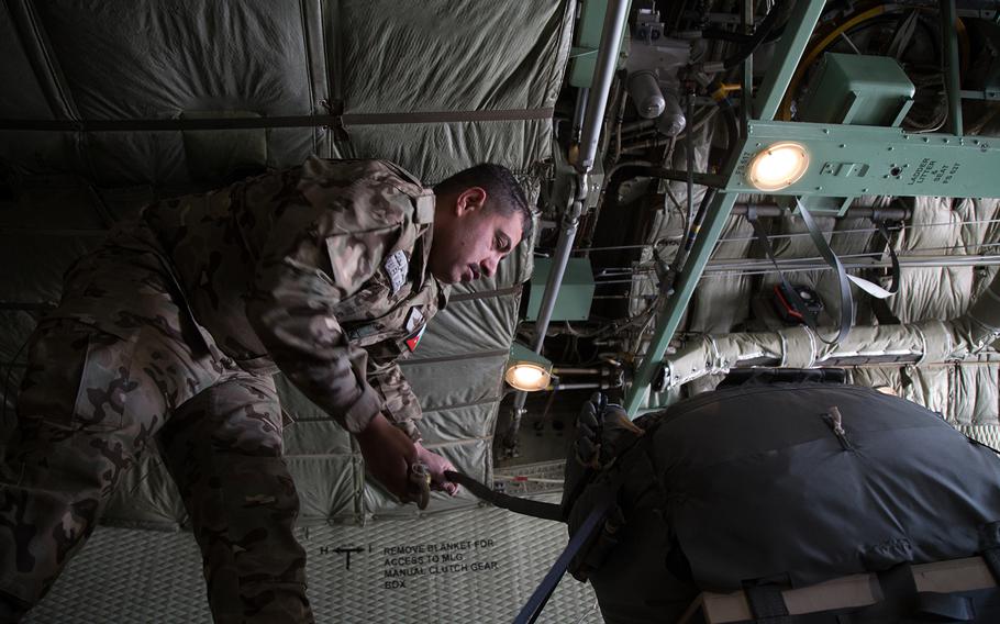 A member of Jordan's air force inspects the parachute ropes on a crate before deployment.