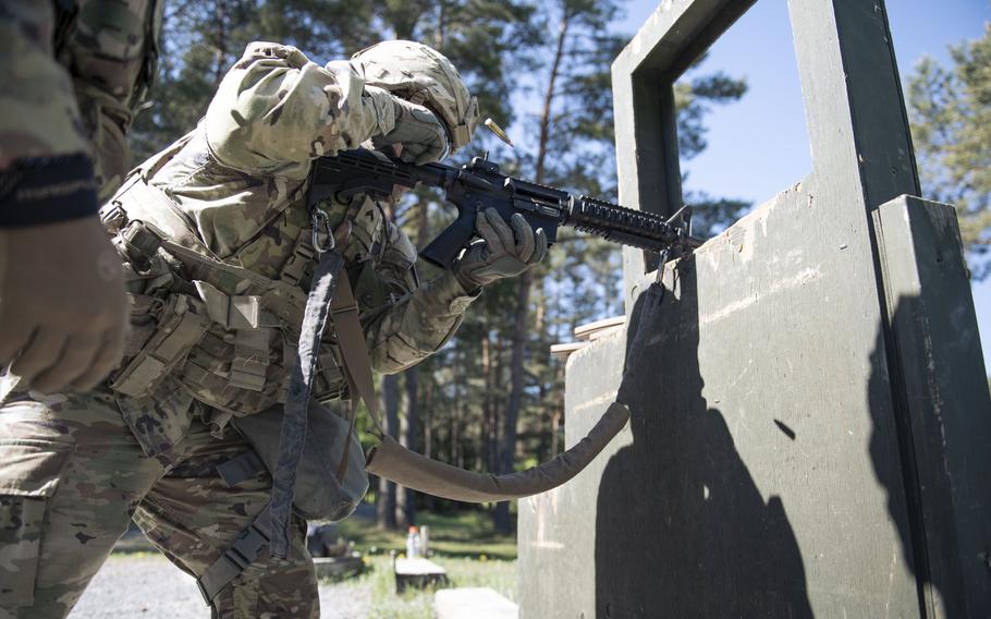 A soldier aims a rifle through a structure.