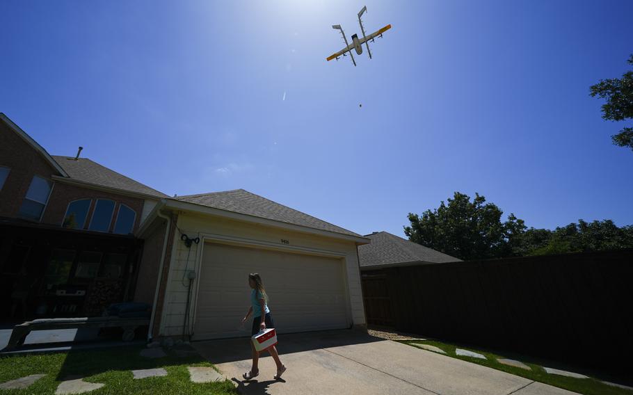A girl carries a bag in front of her house.