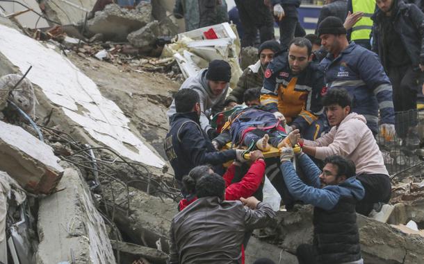 People and emergency teams rescue a person on a stretcher from a collapsed building in Adana, Turkey, Monday, Feb. 6, 2023. A powerful quake has knocked down multiple buildings in southeast Turkey and Syria and many casualties are feared.