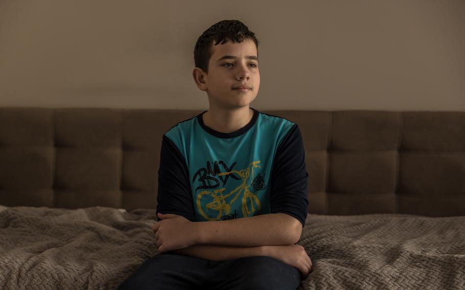 A boy sits inside on a couch.