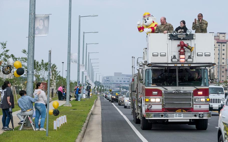 Garrison commander Col. Michael Tremblay and Command Sgt. Maj. Benjamin Lemon ride atop a fire engine during a reverse parade for graduating high school seniors at Camp Humphreys, South Korea, Thursday, May 27, 2021.