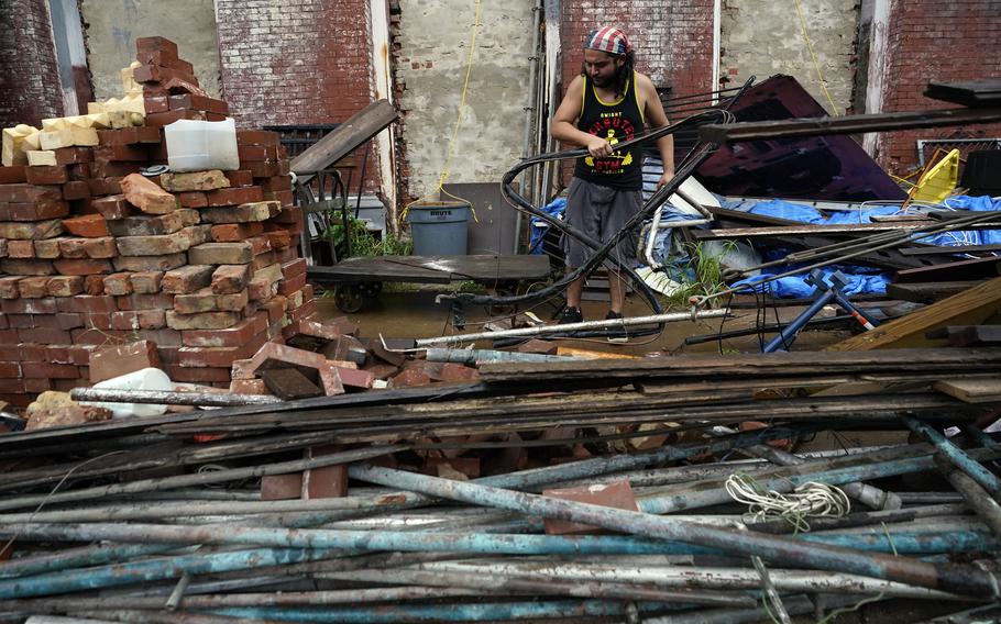 Adrian Bentancourt cleans up debris from a fence that was blow down by Hurricane Nicholas Tuesday, Sept. 14, 2021, in Galveston, Texas.