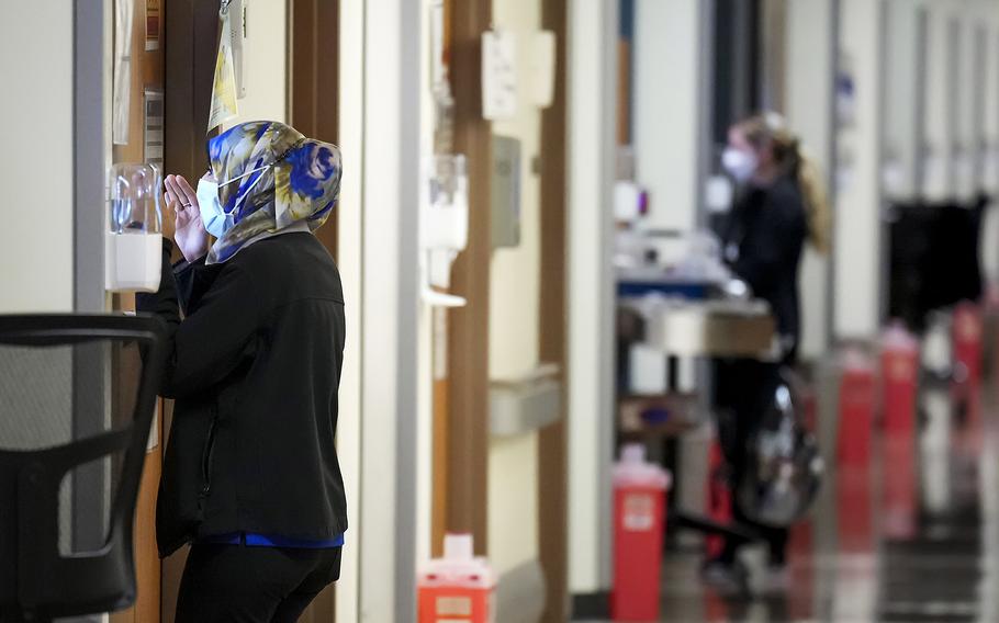 Nurse Fara Ajani, associate manager in medical services, peeks through the window of a patient room while making rounds in the COVID-19 unit at Parkland Hospital on Wednesday, Jan. 5, 2022, in Dallas.