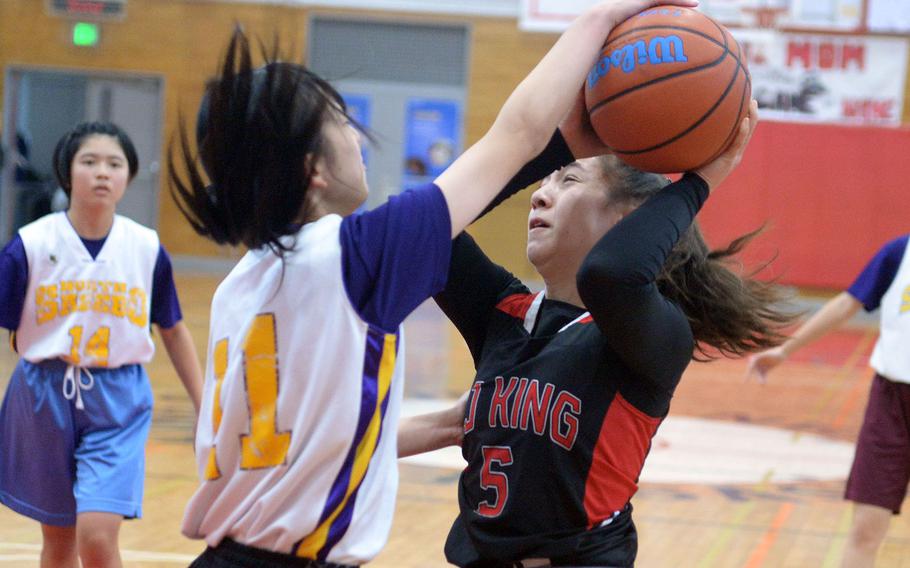 E.J. King's Maliwan Schinker has her shot attempt blocked by Sasebo North's Rika Yamaguchi during Saturday's Japan girls basketball game. The Cobras won 65-38.