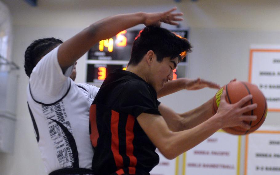 E.J. King’s Nolan FitzGerald shields a rebound from Amari King of Zama during Thursday’s DODEA-Japan boys basketball tournament game. The Trojans won 65-56.