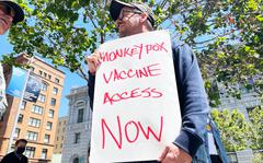 A man holds a sign urging increased access to the monkeypox vaccine during a protest in San Francisco.