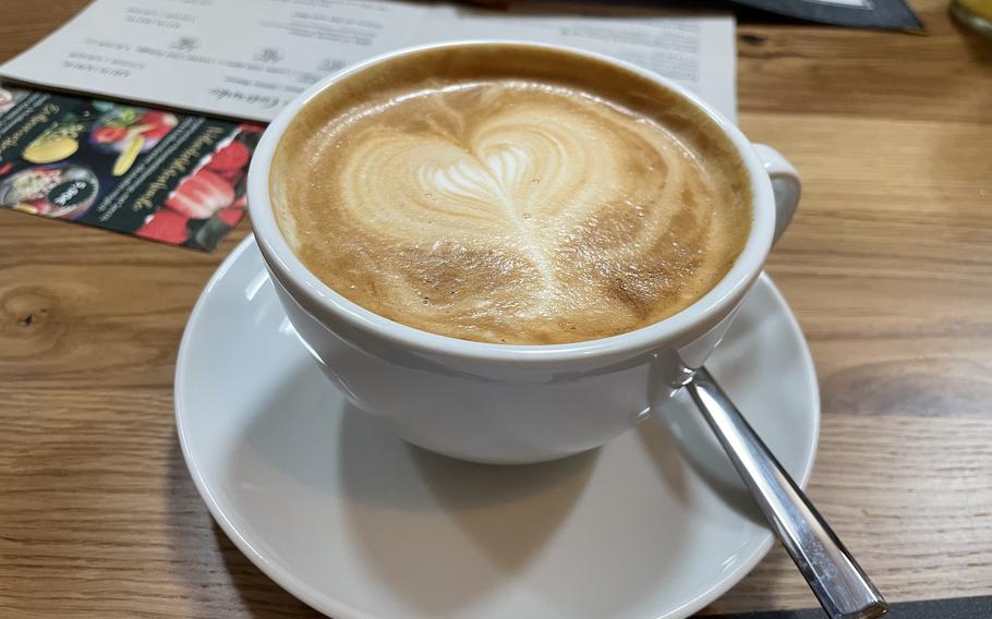 A coffee drink topped with foam poured in the shape of a heart.