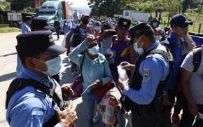 Honduran police check documents of migrants who are part of a caravan hoping to reach the United States, in Corinto, Honduras, Saturday, Jan. 15, 2022. 