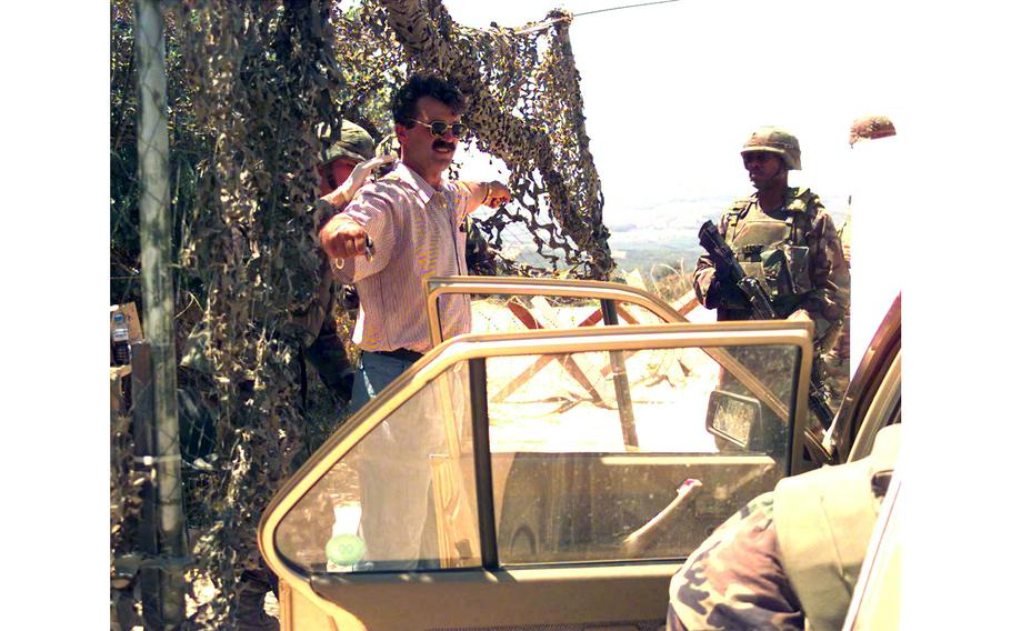 Sgt. Robert Lewis searches a local ethnic Albanian for illegal weapons, as Spc. Cameron McCullough keeps watch, July 6, 2000. Vehicles that enter and exit Check Point Sapper must be checked.