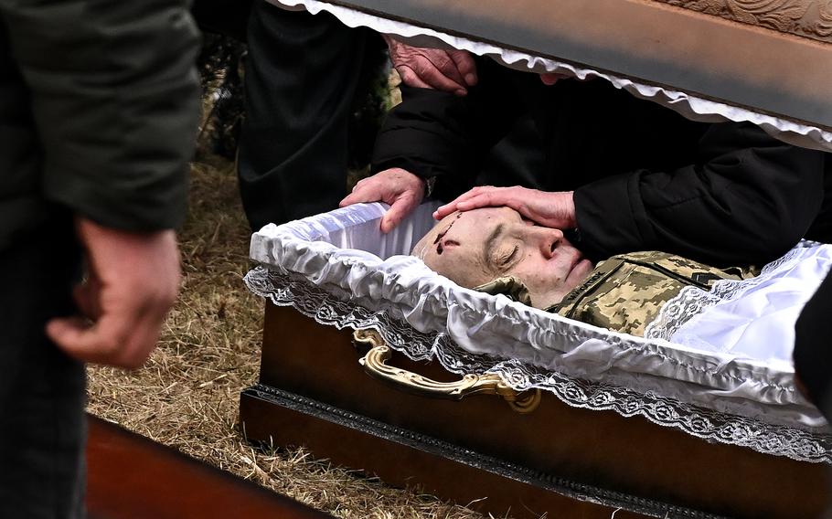 A mourner touches the forehead of a Ukrainian soldier during a funeral on Wednesday, March 16, 2022.
