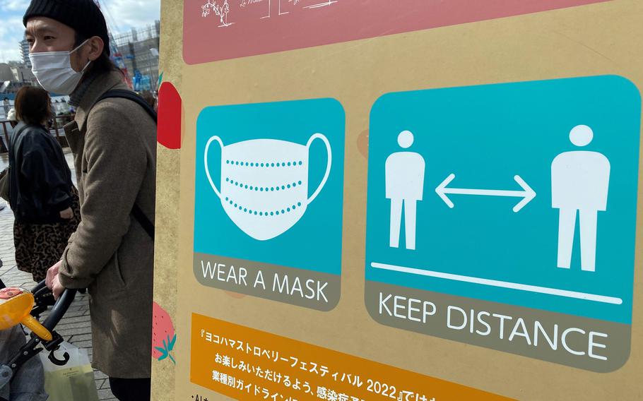 A sign reminds visitors to wear masks and keep their distance at Red Brick Warehouse in Yokohama, Japan, Sunday, Feb. 20, 2022.