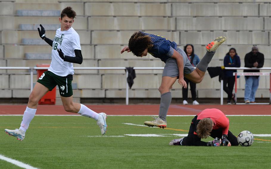 Ansbach’s Daeveon Brown goes flying over AFNORTH keeper Santi Aponte after Aponte blocked the ball on a fast break by the Cougars. Ansbach defeated AFNORTH 5-3 in a Division III semifinal at the DODEA-Europe soccer finals in Kaiserslautern, Germany, May 17, 2023. At left, Nathan Goldsmith watches the action.