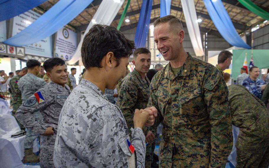 A Marine in uniform bumps fists with a Filipino service member, also in uniform.