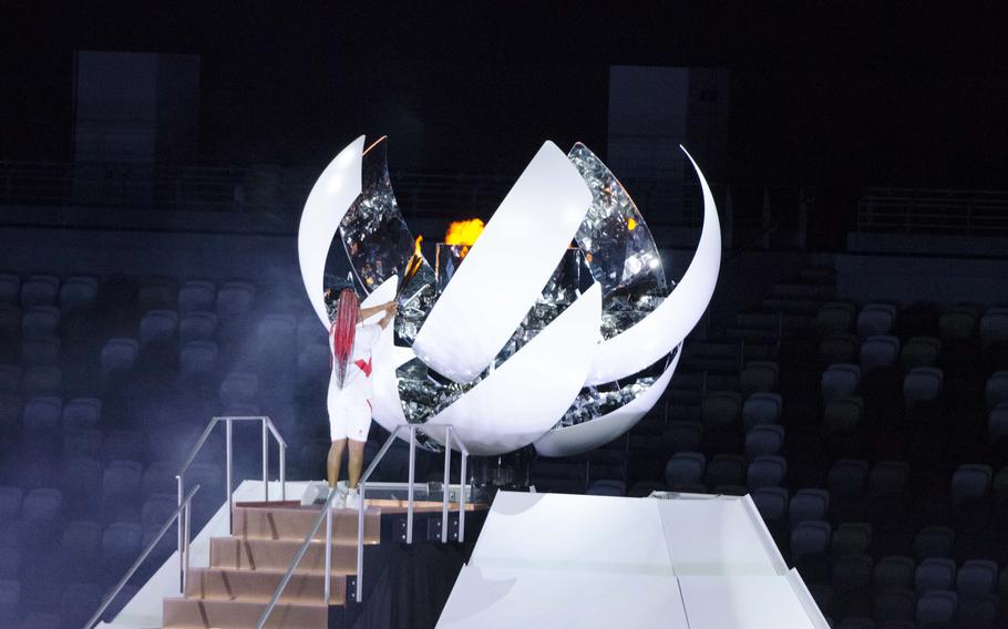 Tennis star Naomi Osaka of Japan stands in front of the Olympic flame after igniting it during the Tokyo 2020 opening ceremony. 