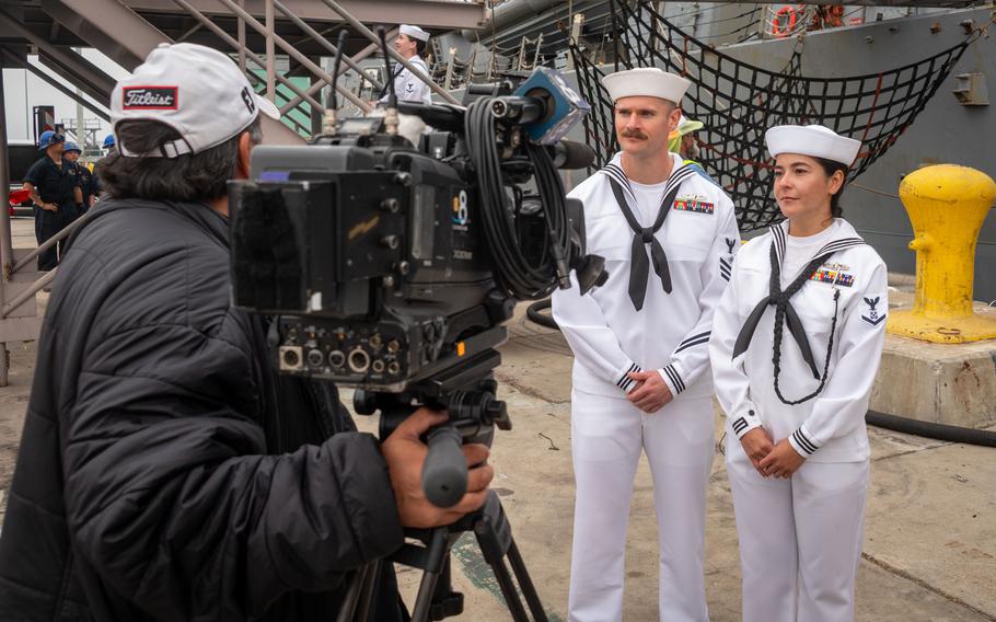 A TV camera operator interviews two sailors.