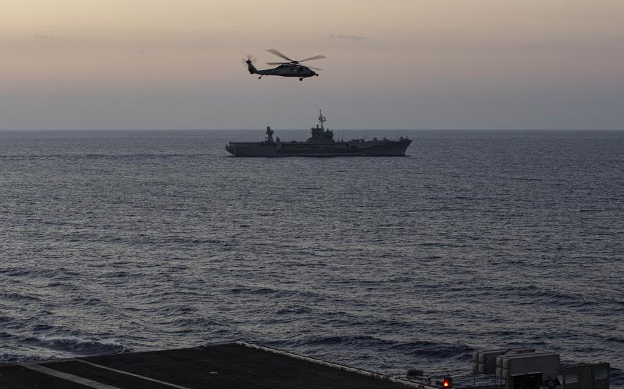 The USS Mount Whitney, a Blue Ridge-class command ship, steams alongside the aircraft carrier USS Gerald R. Ford while an MH-60S Sea Hawk performs a flyby in the Mediterranean Sea on Oct. 3, 2023. 