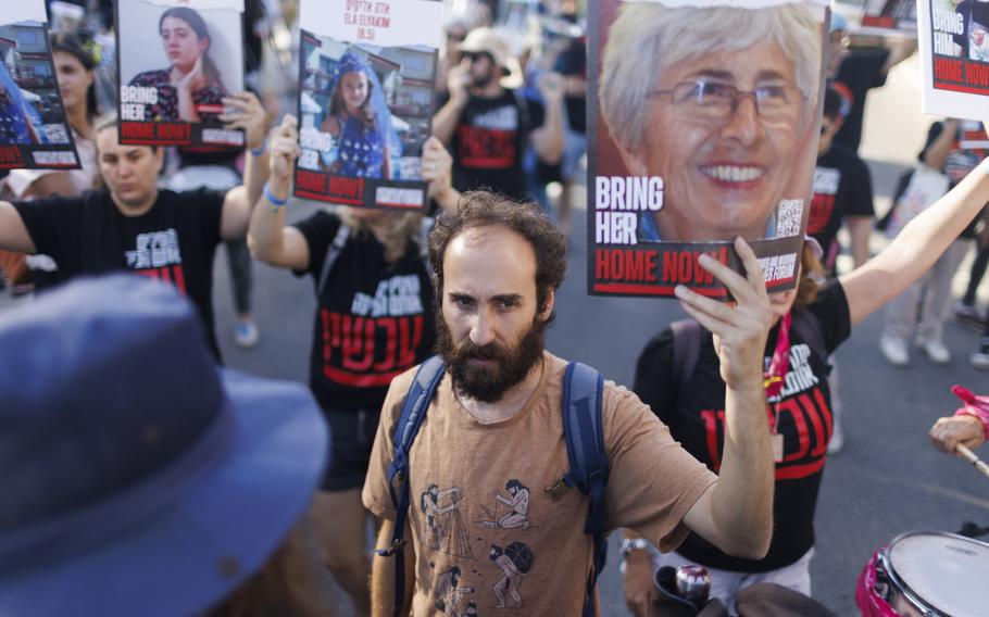 Yonatan, center, holds a photo of his mother during a protest calling for the release of the hostages held in Gaza, in Jerusalem on Tuesday, Nov. 7, 2023.