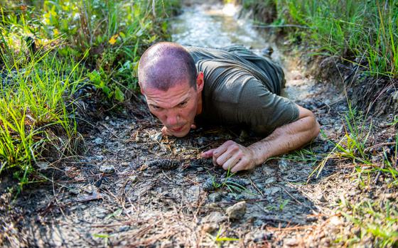 (FORT BENNING, GA) - A Ranger student executes a low crawl through water and under barbed-wire at the Darby Queen obstacle course.  This obstacle, like all of the challenges at the Darby Queen, is designed to test the student’s physical fitness and stress their bodies. (U.S. Army photo by Patrick A. Albright, Maneuver Center of Excellence and Fort Benning Public Affairs)