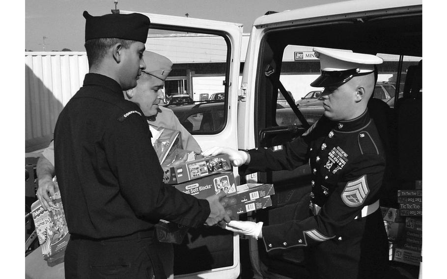 Toys for Tots coordinator Staff Sgt. Christopher Rosenfelt takes a handful of toys from area Latino Unidos members Petty Officer 1st Class Luis Lujan (left) and Lt. j.g. Rudy Madrid at the base exchange in Naples, Italy, on Dec. 7, 2004. Latinos Unidos, a Hispanic cultural organization, donated $500 worth of toys to the local Toys for Tots program. While there, Rosenfelt also received a $300 donation from local Federal Express and Boeing employees. Donations to the Naples Toys for Tots program were given to military families needing help during the holidays and local orphanages.