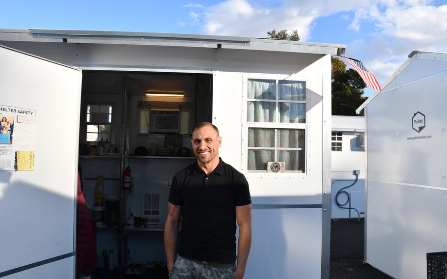 Army veteran Michael Shea, 32, stands in front of his 8-by-8-foot shelter on the grounds of the Department of Veterans Affairs campus in West Los Angeles on Wednesday, Feb. 23, 2022. Shea has lived in the shelter for about three months while saving money for a more permanent home and receiving social services from the VA.