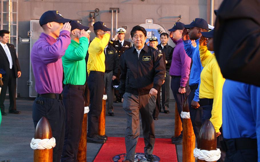 Japanese Prime Minister Shinzo Abe walks through rainbow sideboys as he departs the aircraft carrier USS Ronald Reagan on Oct. 18, 2015. 