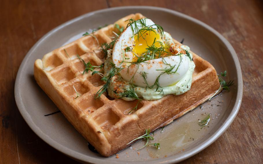 A soft-boiled egg sits atop a waffle.