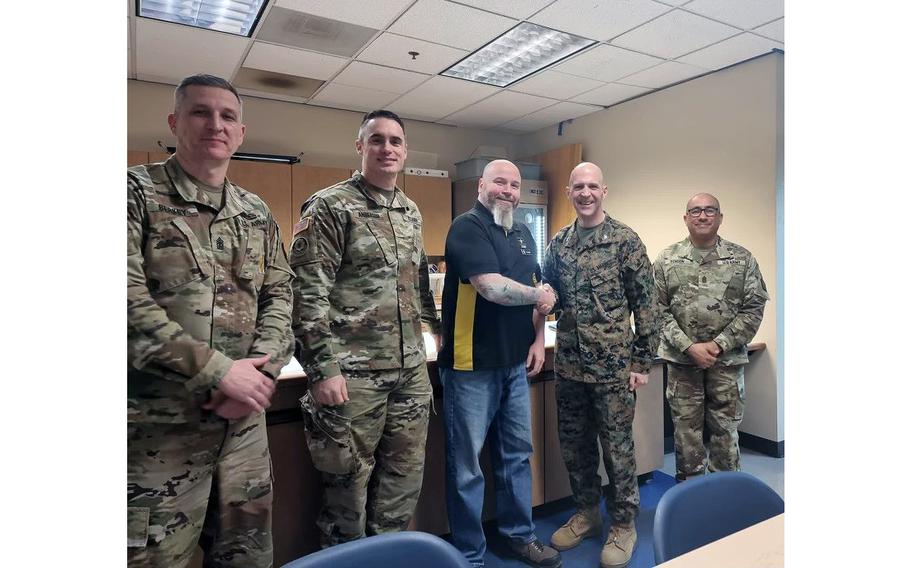 David Foland, administrative support technician, Portland, Ore., MEPS, center, is presented with the Western Sector Coin for Excellence by Marine Corps Col. Jesse Sjoberg, USMEPCOM Western Sector commander. Foland was recognized for intervening and disarming a possible active shooter in Troutdale, Ore.