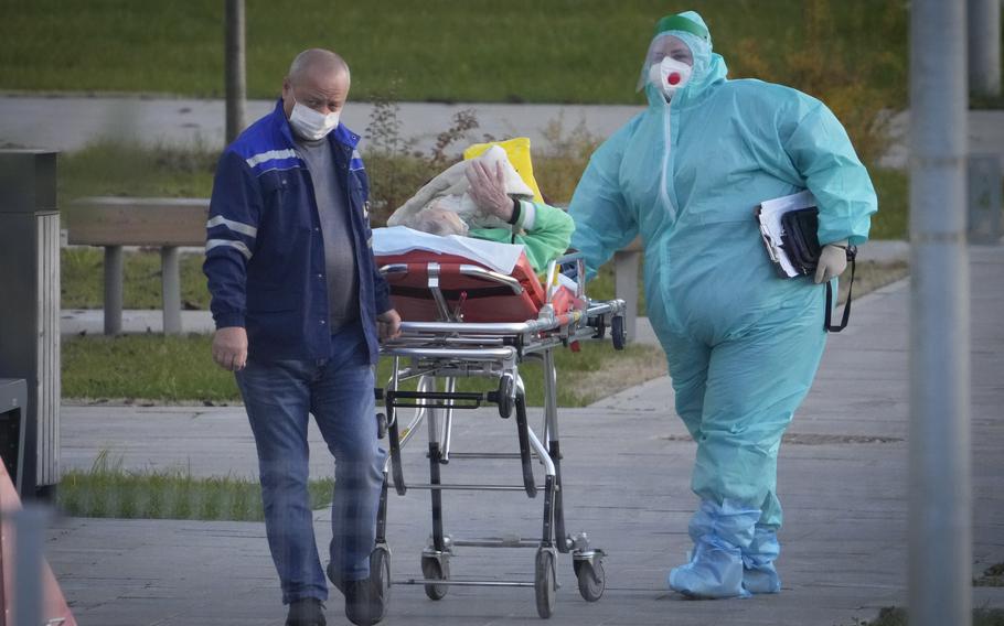 Medical workers carry a patient suspected of having coronavirus on a stretcher at a hospital in Kommunarka, outside Moscow, Russia, Monday, Oct. 11, 2021. Russia’s daily coronavirus infections and deaths are hovering near all-time highs amid a laggard vaccination rate and the Kremlin’s reluctance to toughen restrictions. Russia’s state coronavirus task force reported 29,409 new confirmed cases Monday. That’s the highest number since the start of the year and just slightly lower than the pandemic record reached in December.