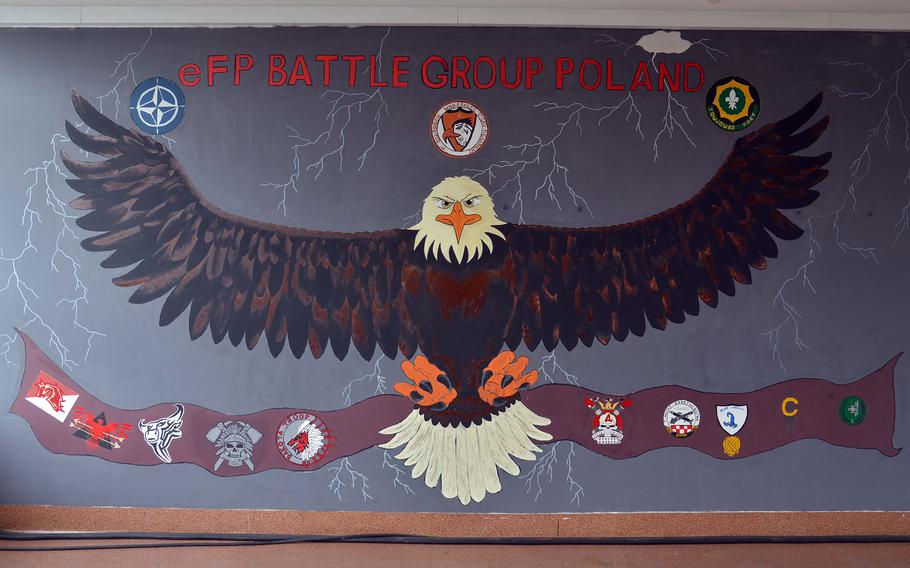On a mural in the headquarters building of NATO's Enhanced Forward Presence Battle Group Poland, an eagle soars among the emblems of the multinational unit stationed at a Polish military base in Bemowo Piskie. The soldiers of 1st Squadron, 2nd Cavalry Regiment ⁠— the War Eagles ⁠— are returning to Vilseck, Germany and being replaced by 2nd Squadron, 278th Armored Cavalry Regiment.