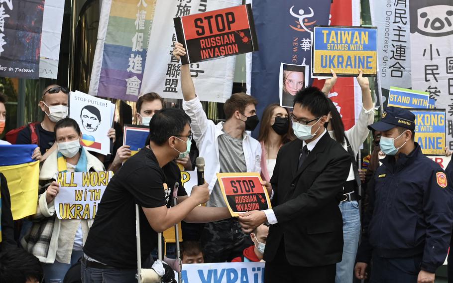 A staff member, center right, from the Russian representative office receives a protest sign from a demonstrator during a protest against Russia's invasion of Ukraine, outside the Russian representative office in Taipei, Taiwan, on March 1, 2022. 