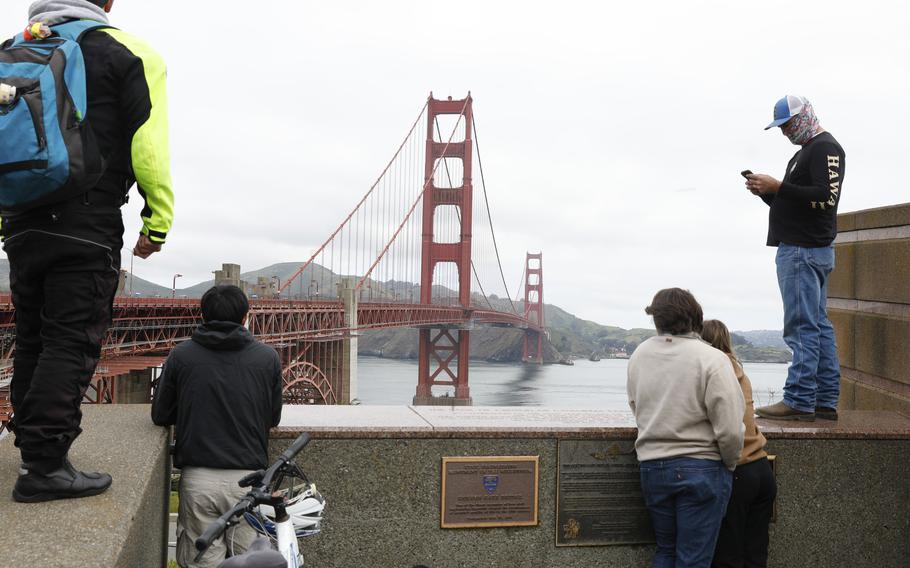 Pedestrians and bicyclists wait outside the pedestrian gate on the south side of the Golden Gate Bridge while the bridge is closed due to protesters on Monday, April 15, 2024 in San Francisco, Calif. 