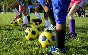 Children stand with soccer balls.
