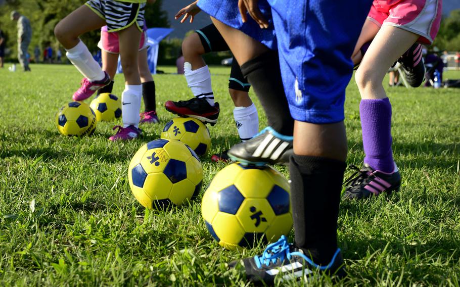 Children stand with soccer balls.