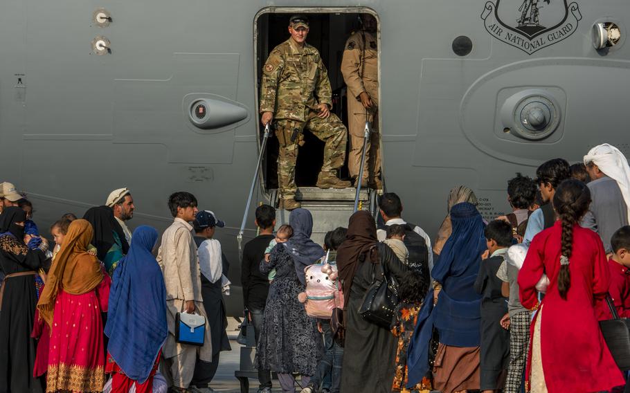 Service members prepare to board Afghan evacuees onto a C-17 Globemaster lll Aug. 22, 2021, at Al Udeid Air Base, Qatar. 