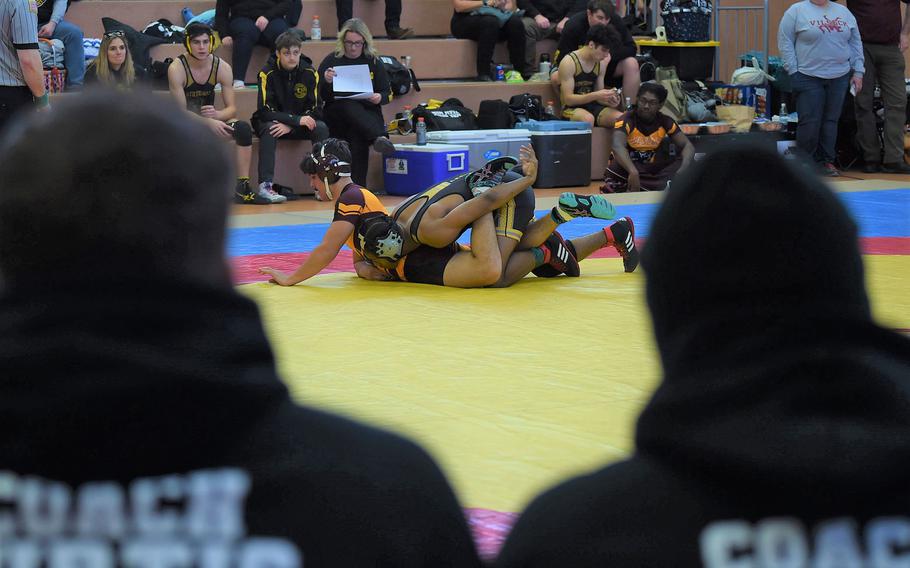 Stuttgart senior Josiah Doughty throws Vilseck senior Pierre Fuentes to the mat as both Stuttgart coaches watch on. Doughty closed out the 150-pound weight class with his third win of the day against Fuentes.