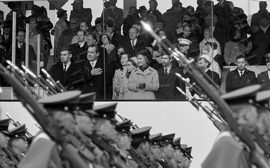 Cadets with guns on the shoulders march past the reviewing stand.