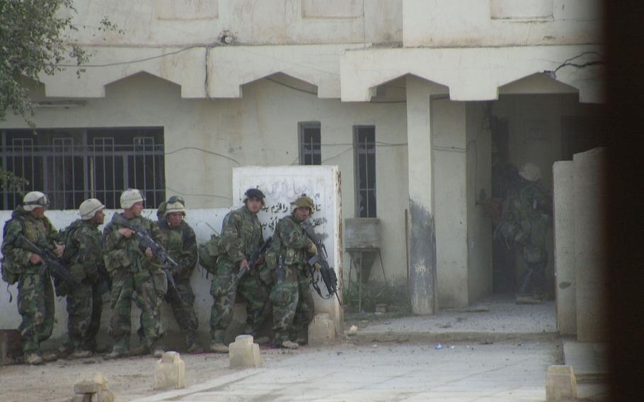 Marines stack along a wall outside the Baath Party headquarters building in Al Fahr during a raid. Company G, 2nd Battalion, 23rd Marines found a large cache of weapons and documents, including some written in German bearing the radiological symbol.                   