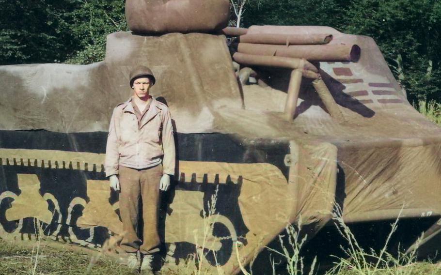 A Ghost Army soldier stands next to an inflatable tank used to deceive enemies in World War II.