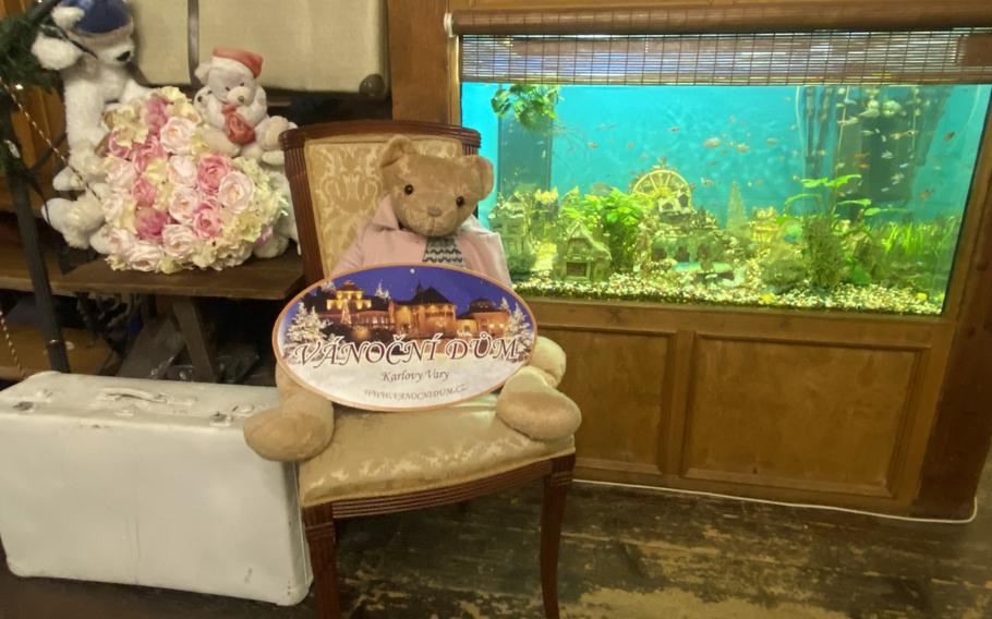 An aquarium and a solitary teddy bear holding a Christmas House sign adorn one side of the Czech attraction's cafe. This section also has a stairway whose railing is lined from end to end with miniature teddy bears.