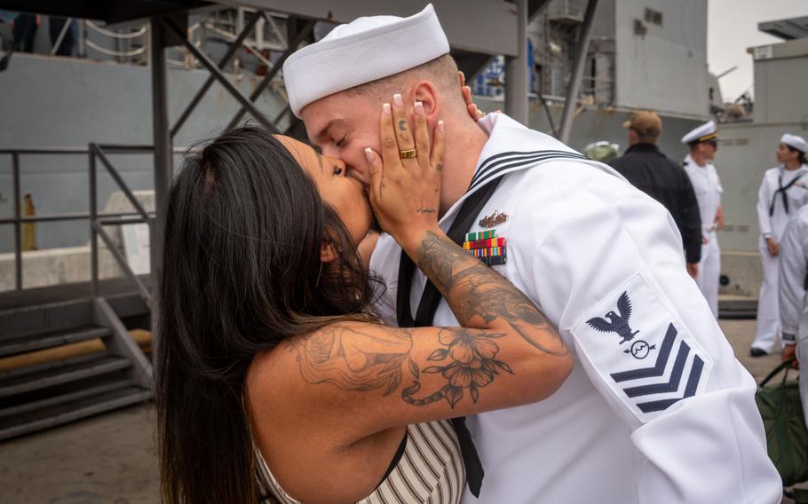 A sailor plants a big kiss on his wife’s lips.