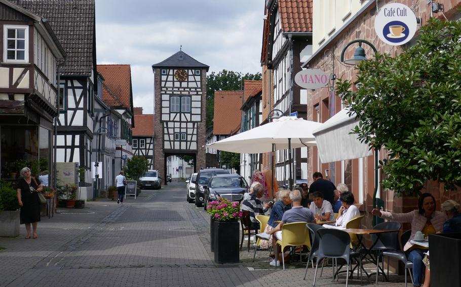 People sit at a cafe on Fahrgasse in Dreieichenhain, Germany. In the background is the Obertor, one of the two tower gates that bookend the street. The town, about 30 miles east of Wiesbaden, is known for its colorful half-timbered houses and its medieval castle.