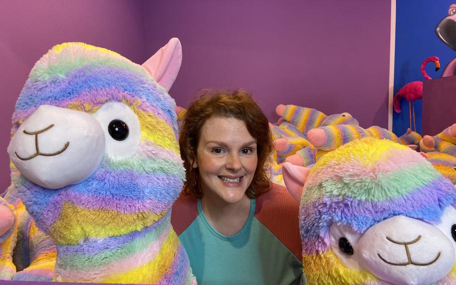 Ann Pinson poses with a pair of rainbow-colored llamas Oct. 21, 2021, at SnapMySelf in downtown Kaiserslautern, Germany. The llama pit is one of nearly two dozen sets or backdrops in the ''selfie museum.''
