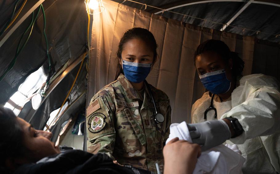 Air Force Capt. Danielle Holland, left, an OB-GYN physician at RAF Lakenheath, United Kingdom, and U.S. Army Lt. Col. L. Rene Key,  director of the Carl R. Darnall Army Medical Center OB-GYN course at Ft. Hood, Texas, provide medical care to an evacuee at Ramstein Air Base, Germany, Aug. 31, 2021. A field hospital and medical tent with OB-GYN care is available for expectant mothers and newborn babies in need of emergency treatment. 