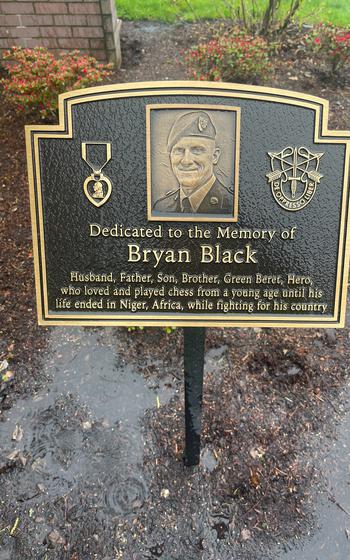 A memorial plaque with Black’s likeness posted in a flower bed in the park.