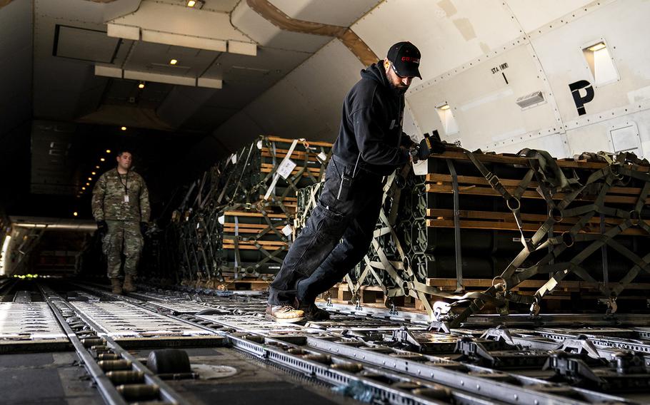 Workers lock pallets of ammunition, weapons and other equipment. 