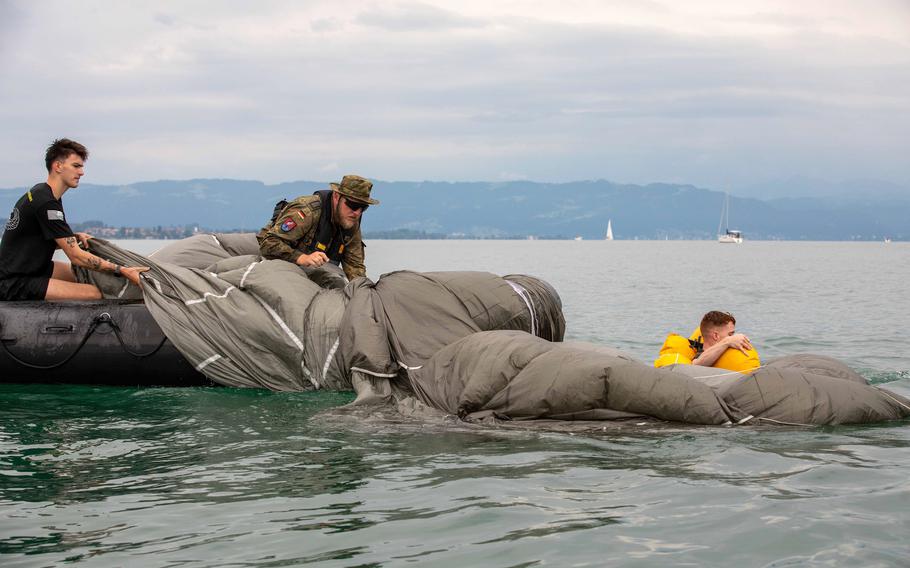 German soldiers recover a parachute before assisting a paratrooper with the 173rd Brigade Support Battalion, 173rd Airborne Brigade, during a jump onto Lake Constance, Germany, Friday, July 29, 2022. About 70 paratroopers from the brigade participated along with 75 German paratroopers from the 26th (Saarland) Airborne Brigade.