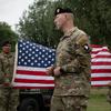 A U.S. soldier speaks in front of an American flag.