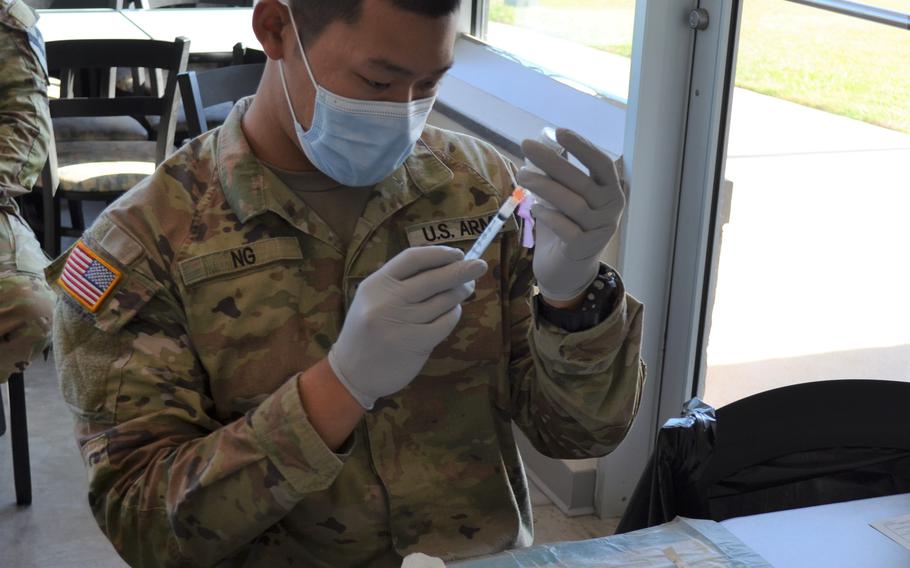 Spc. Michael Ng, a combat medic with 1st Battalion, 12th Cavalry Regiment at Fort Hood, Texas, prepares coronavirus vaccines Wednesday at a pop-up clinic at a base food court. The outreach has provided more than 600 vaccines to soldiers and families. 